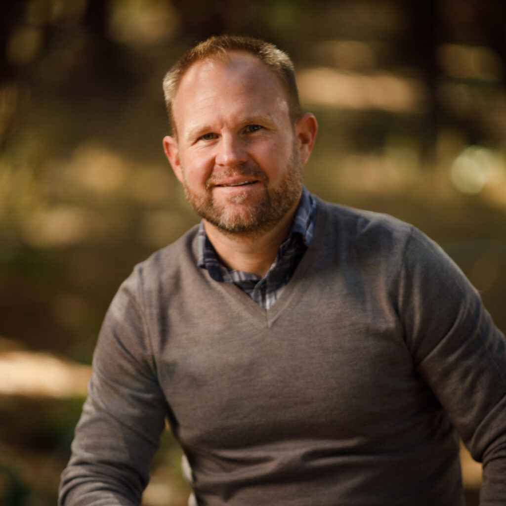 A man sitting on a bench in the woods.