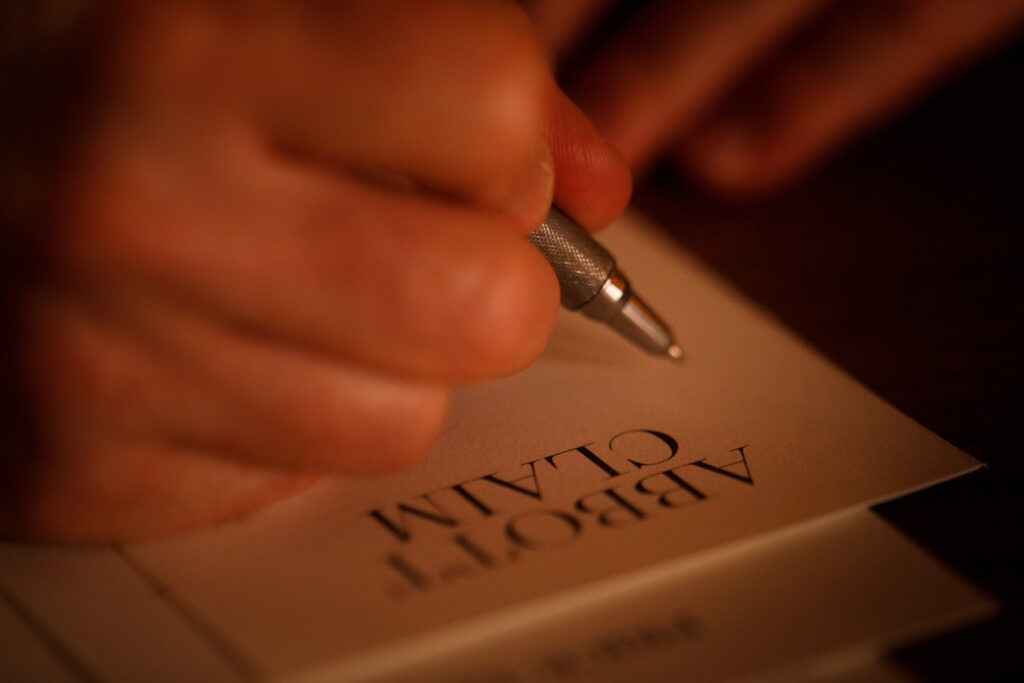 A person writing on a piece of paper with a pen.